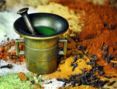Traditional Brass Mortar and Pestle with Vibrant Green Liquid and Aromatic Spices image