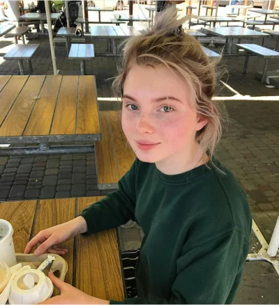 Young woman with freckles smiling at an outdoor cafe