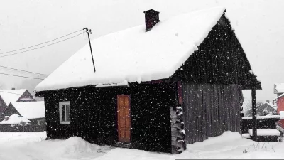 Rustic Wooden House Blanketed in Falling Snow During a Peaceful Winter Day image